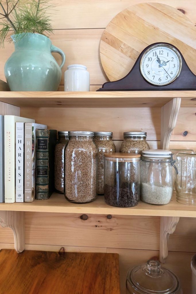 Kitchen shelves with clock, vase, cookbooks and jars of wheat berries