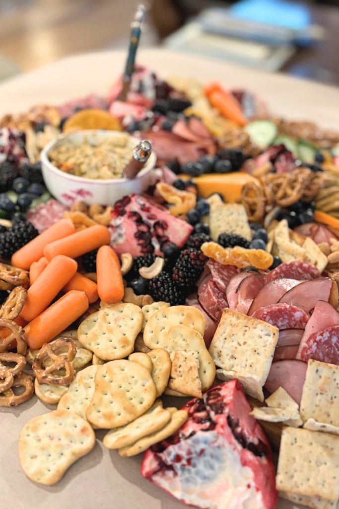 Charcuterie board with meats, cheese, dip, crackers and fruit.