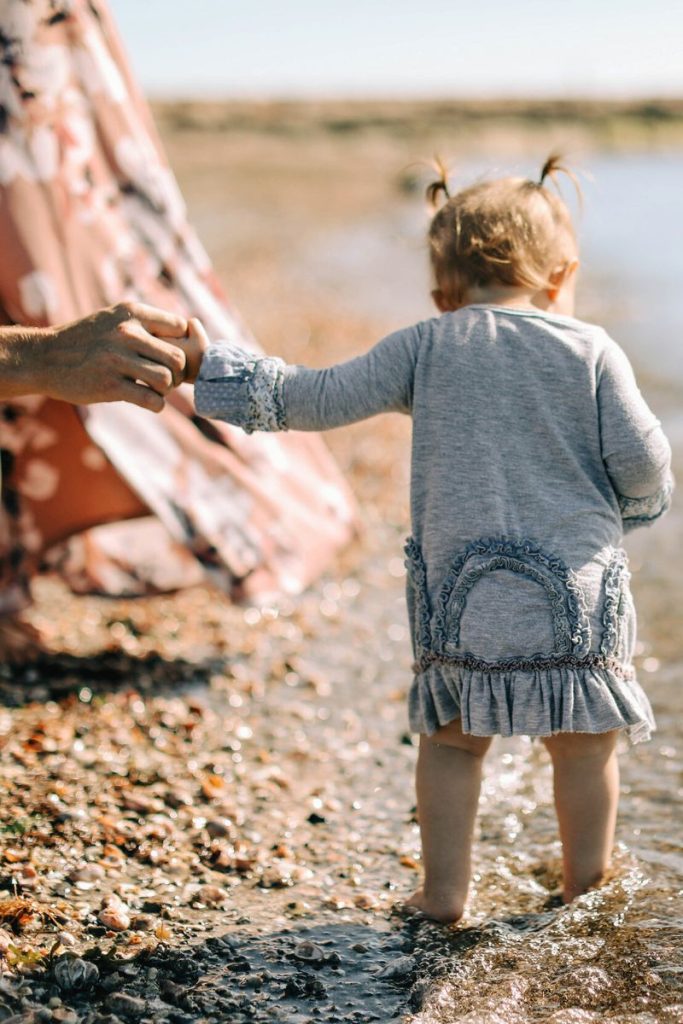 Baby girl holding hand on the beach