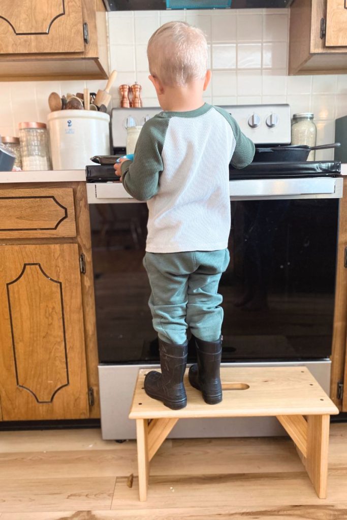 Young boy helping in kitchen by the stove
