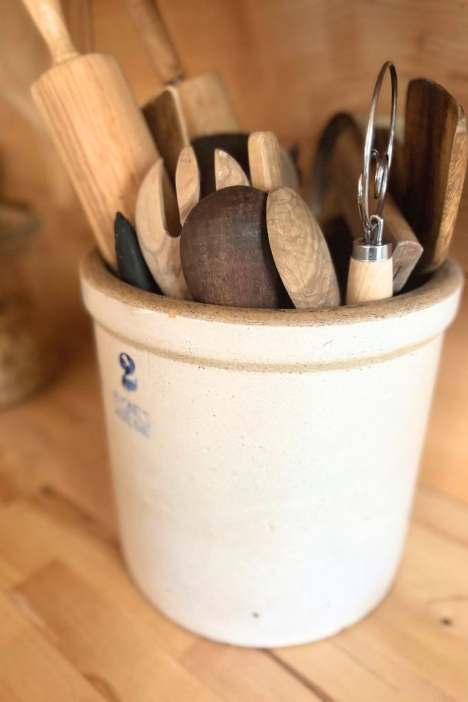 Large crock with wooden kitchen utensils inside