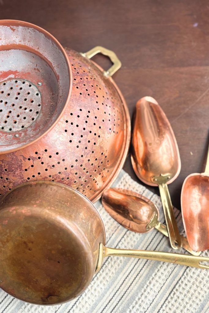 Copper pot, scoops and collander on table